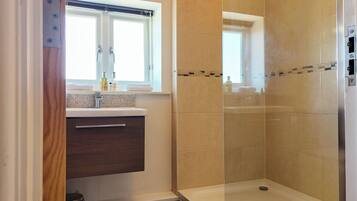 A bathroom with a shower, a window, and a vanity with a sink.