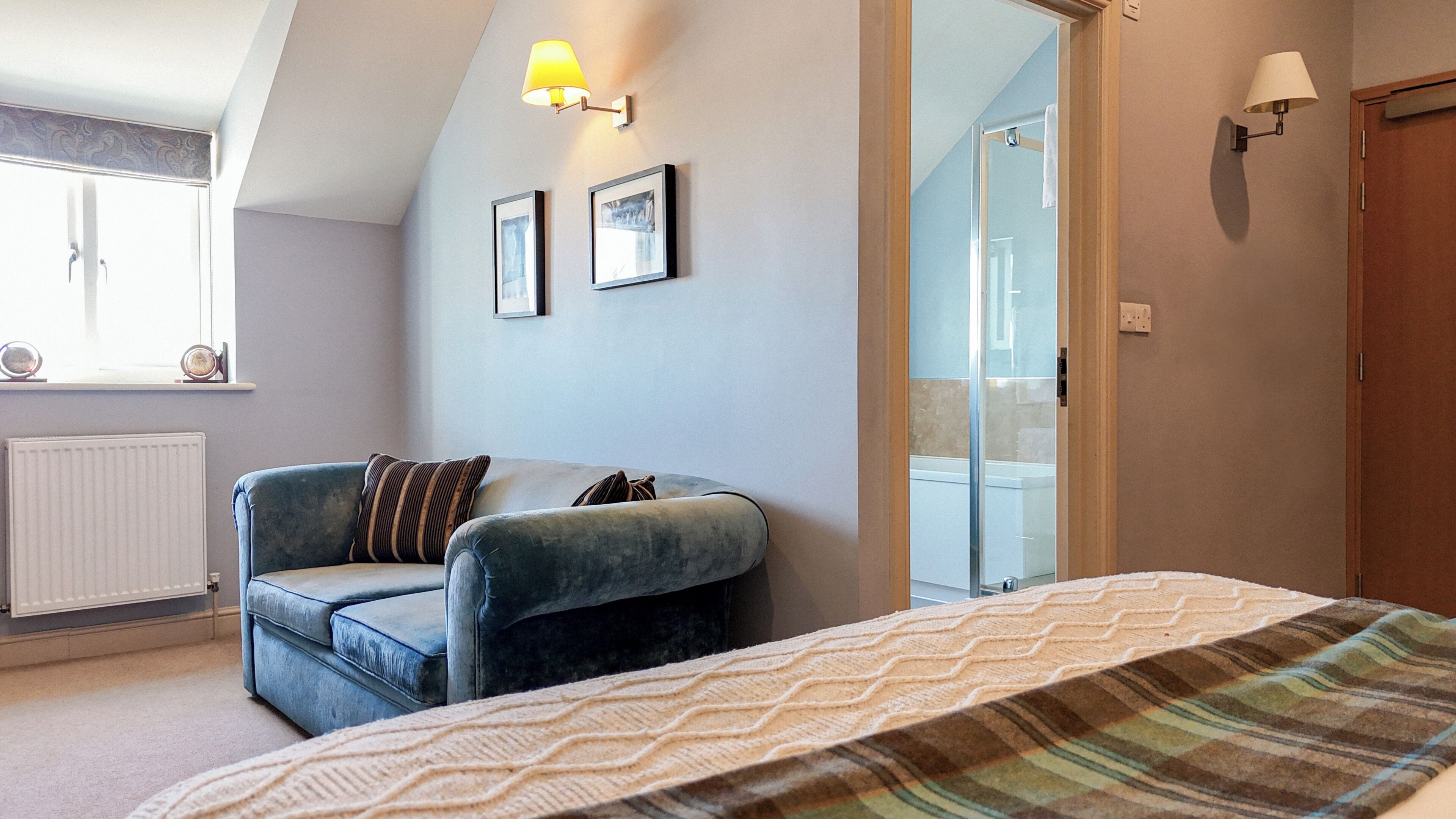 A bedroom with a bed, a chair, a radiator, a window, and a shower.