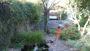 Een tuin met een stenen pad dat naar een vijver met waterornamenten leidt.