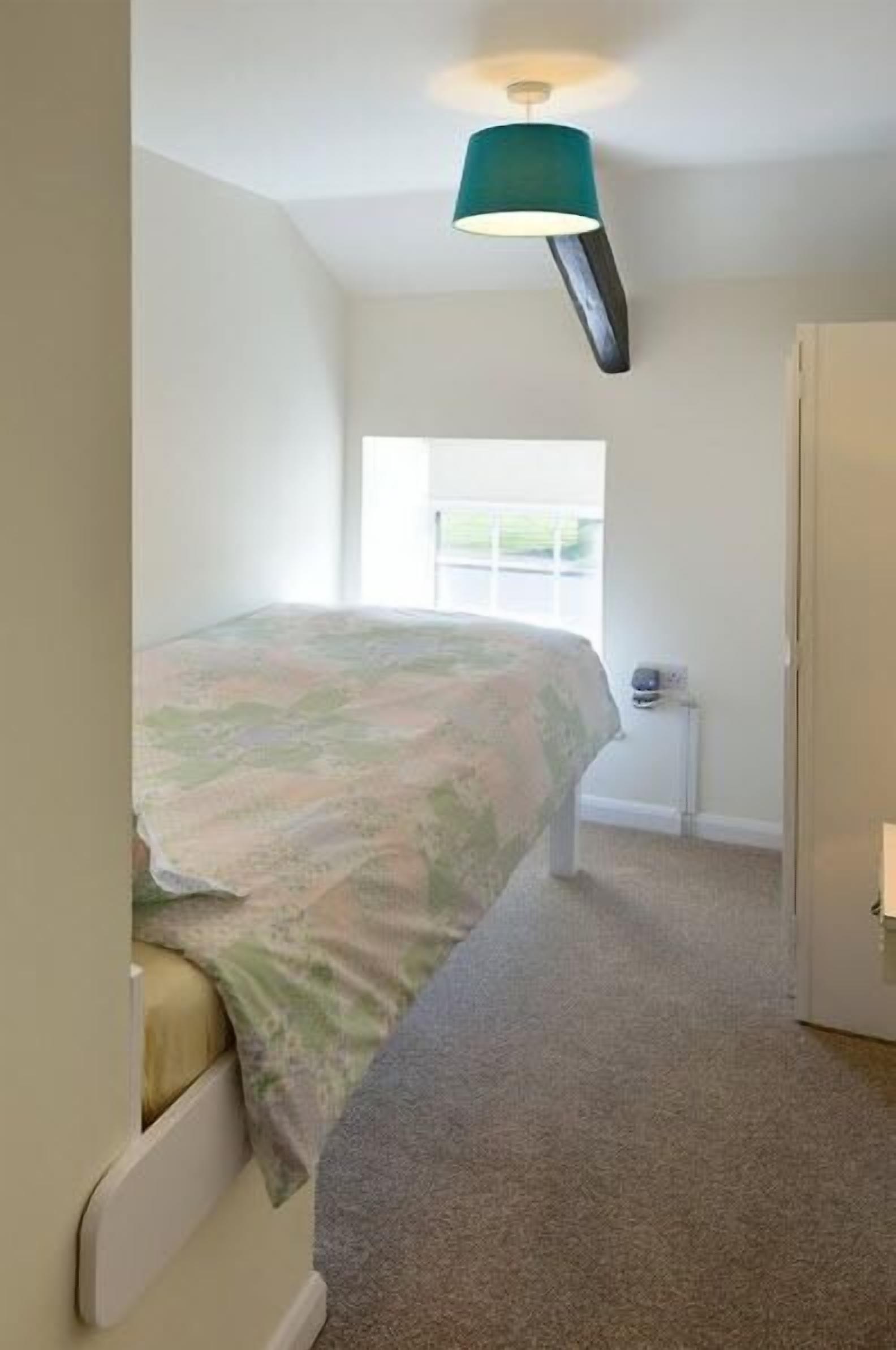 Ein Schlafzimmer mit Bett, Fenster, Tür und Deckenleuchte.