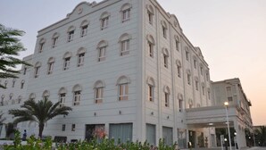 Un edificio de varios pisos con fachada simétrica, ventanas amplias y un área de entrada cubierta.