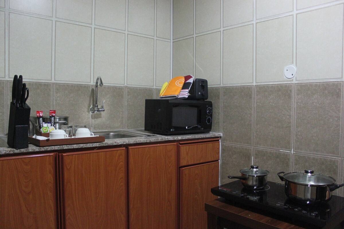 A kitchen with a microwave, toaster, sink, and stove.