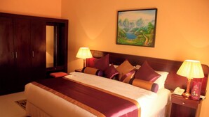 Habitación de hotel con una cama grande, dos lámparas de noche, una mesita de noche con teléfono y un cuadro en la pared.