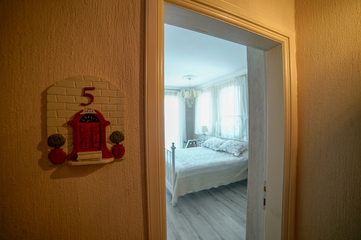 Una habitación con una cama, una puerta con el número 5 y una pared de ladrillo.