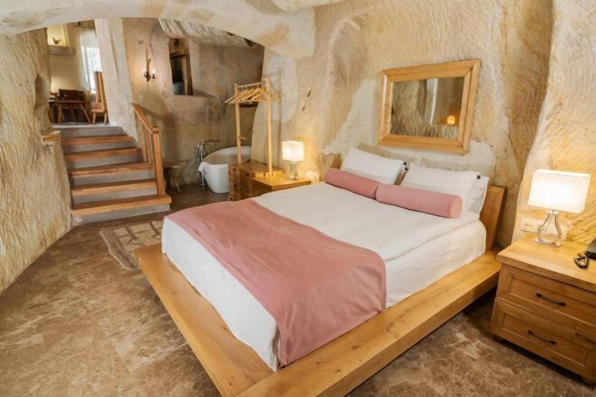 Un dormitorio con una cama de madera, una mesita de noche, un espejo y una escalera que lleva a otra habitación.