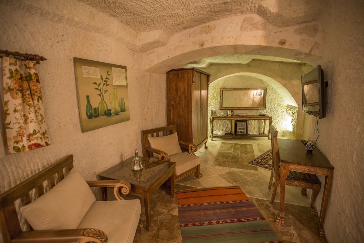Una habitación acogedora con un sofá, una mesa de madera y una televisión. Hay un cuadro en la pared y una alfombra en el suelo.