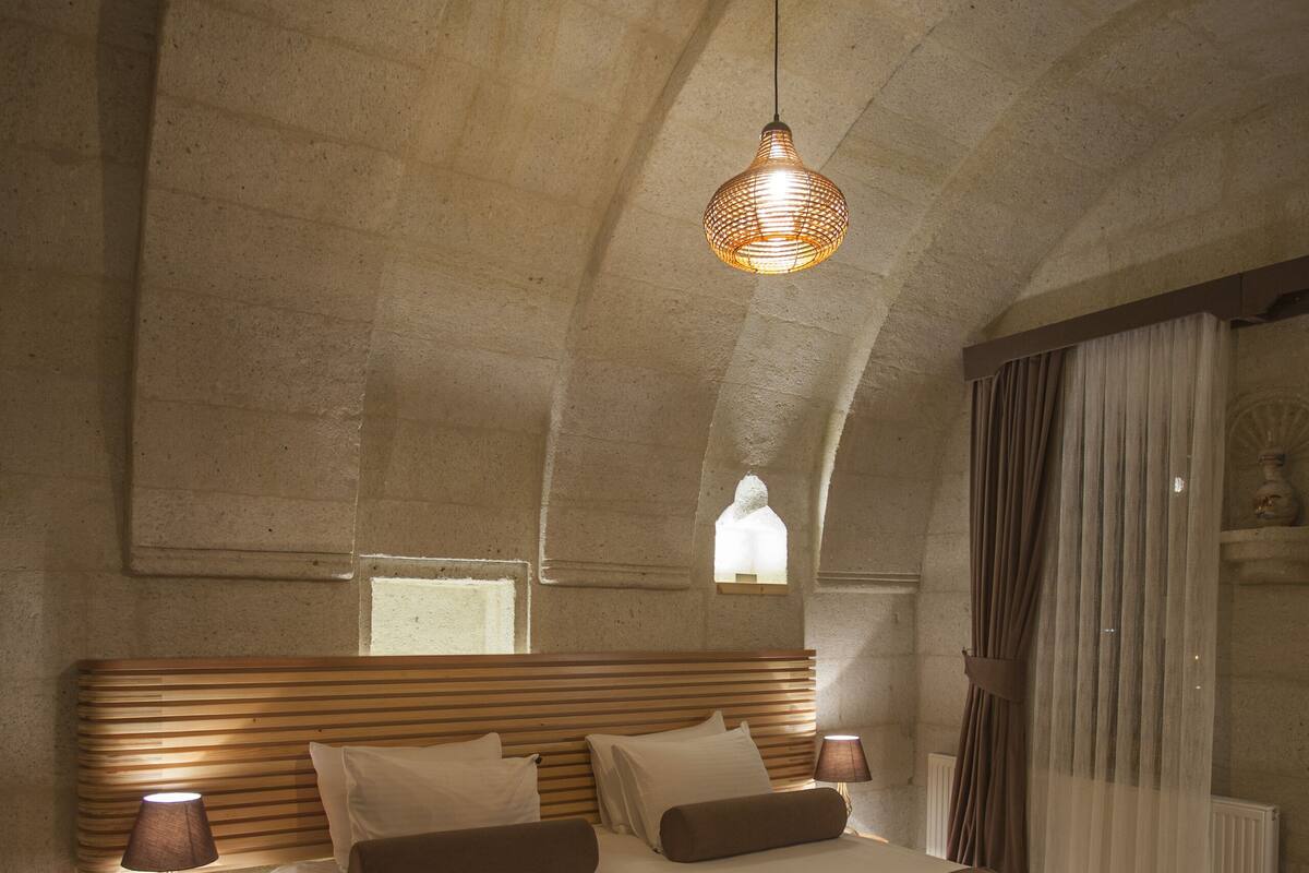 Una habitación amplia con una cama grande, cabecera de madera y una lámpara colgante.