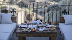Una mesa de comedor con diversos platos y una vista de terreno rocoso al fondo.