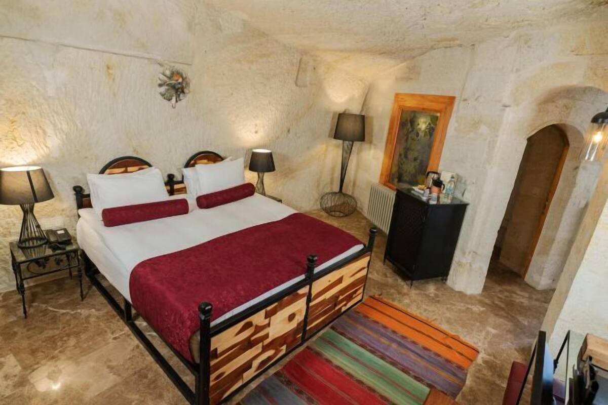 Un dormitorio con cama, mesitas de noche, lámparas, cómoda y alfombra.