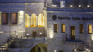 Fachada del Hotel Cueva Agarta con arquitectura de piedra, varios balcones y ventanas iluminadas.