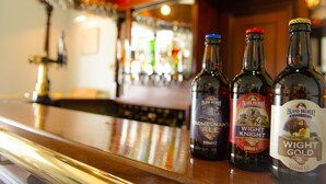 Three bottles of beer on a bar counter with a blurred background of a bar. - The Clifton (Shanklin)