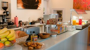 A breakfast buffet with various food items, a coffee machine, and a coffee cup artwork on the wall. - The Clifton (Shanklin)
