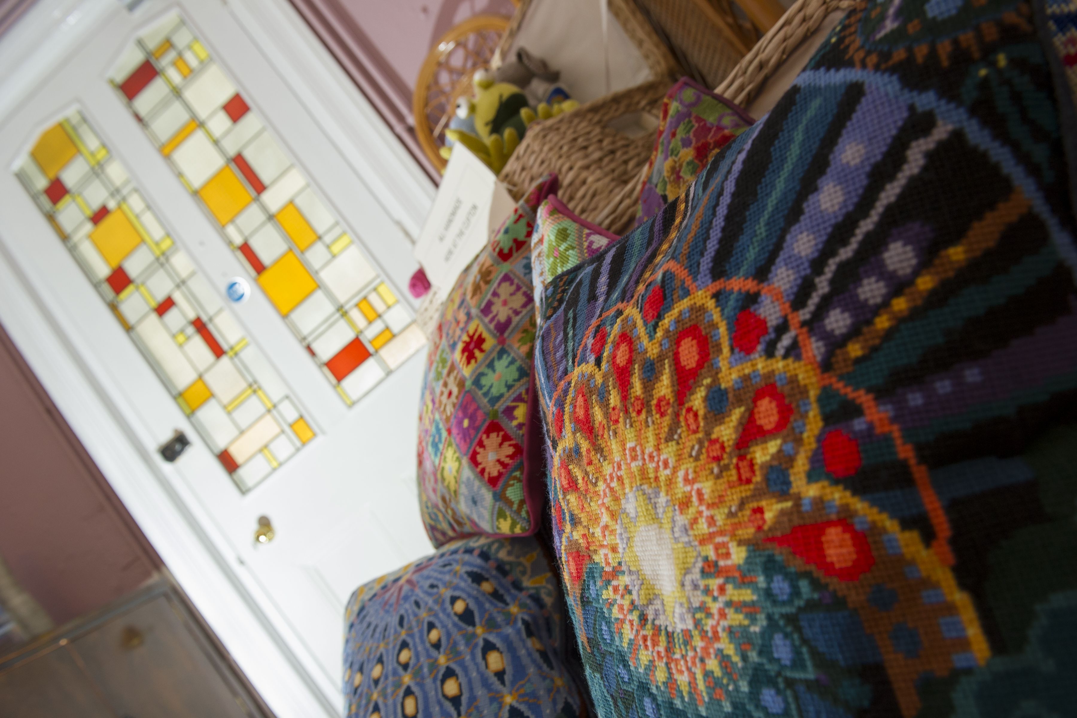 A room with a patterned rug, a wicker chair, and a door with stained glass windows.