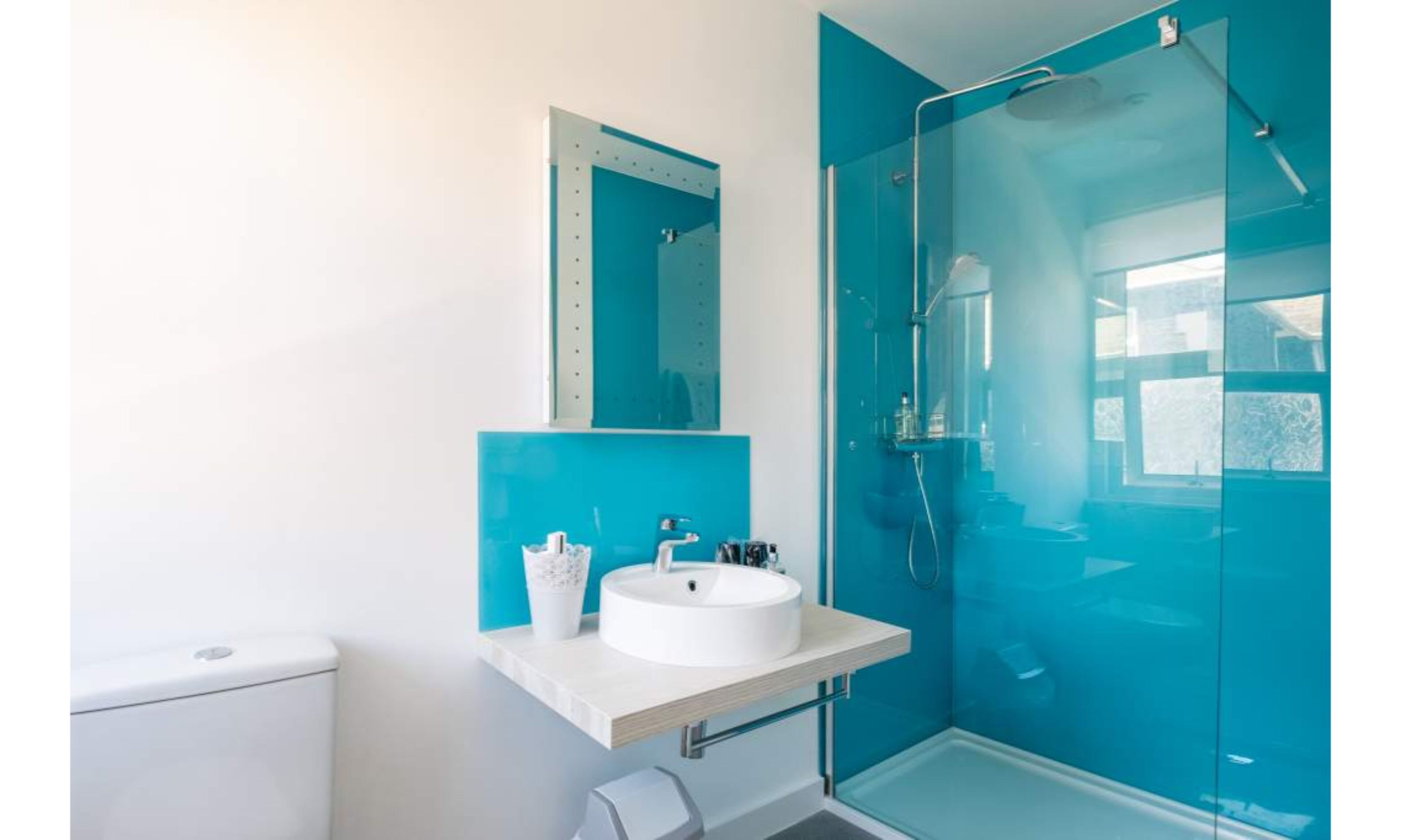 A modern bathroom with a white sink, a mirror, and a glass-enclosed shower.