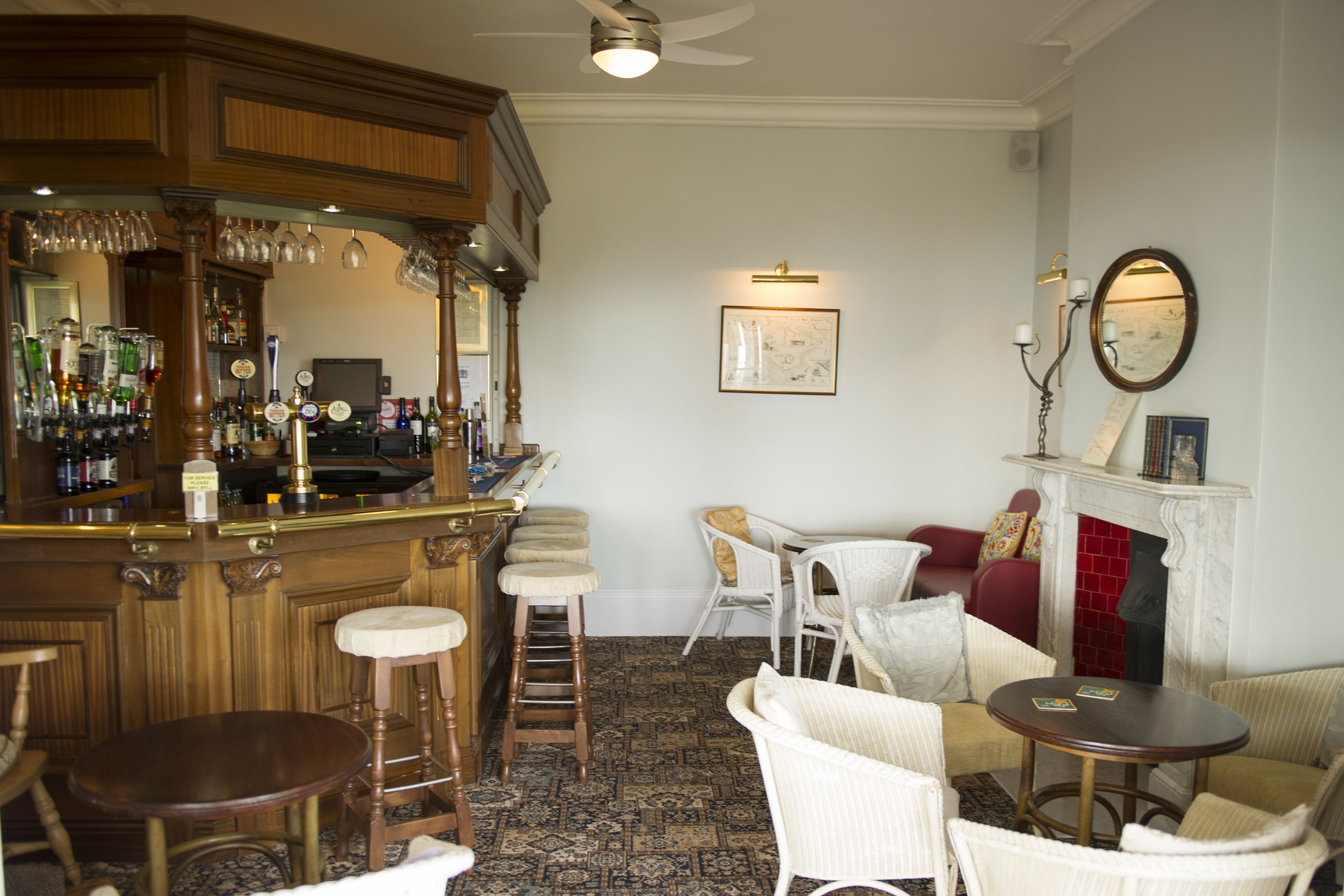 A bar area with stools, a fireplace, and a seating area with chairs and a table.