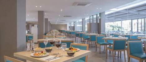 A spacious restaurant with multiple tables and chairs, large windows, and a modern interior design.