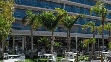 An outdoor dining area with tables and chairs, a plate of food, and a beer mug.