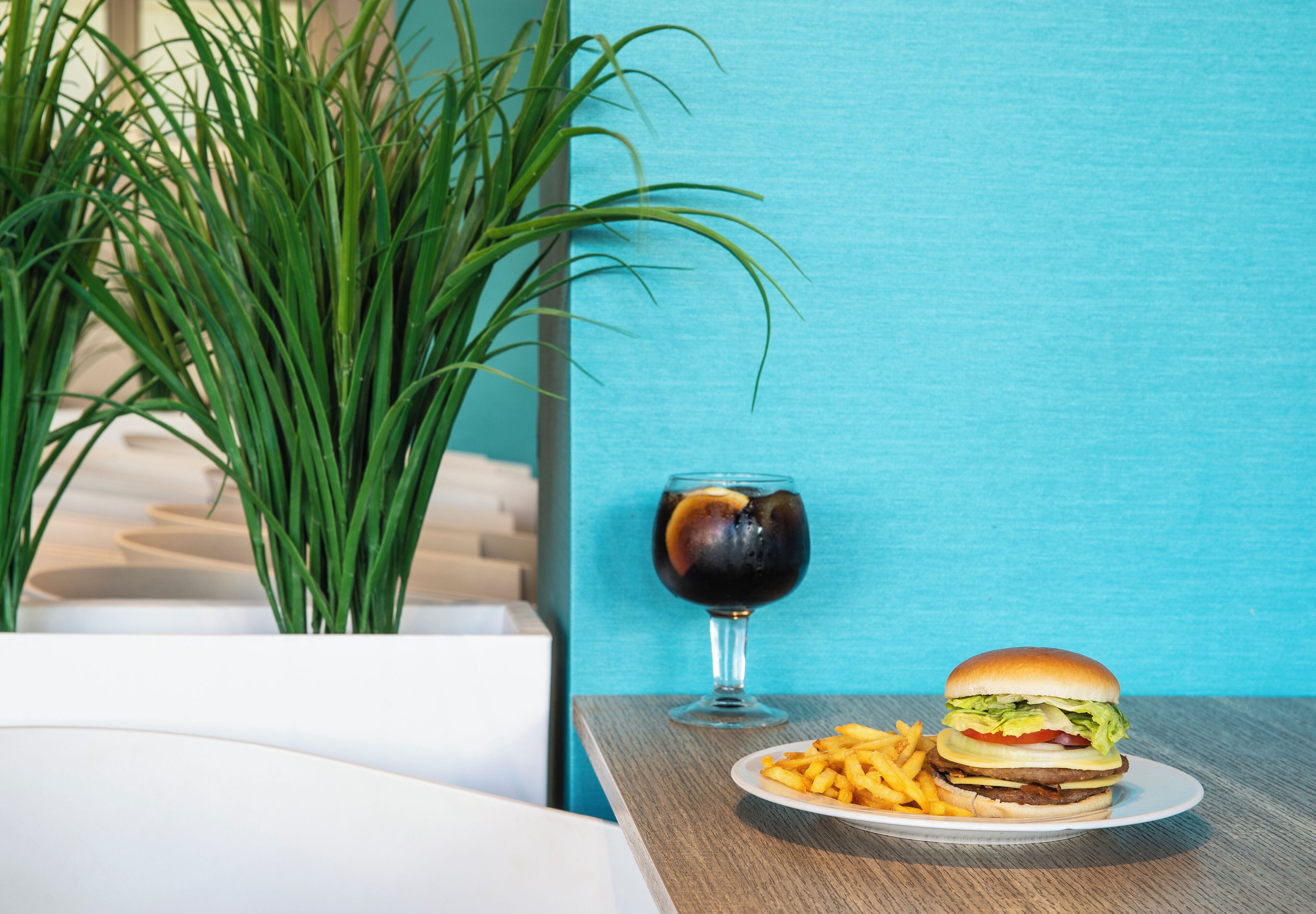 A table with a burger, fries, and a glass of soda.