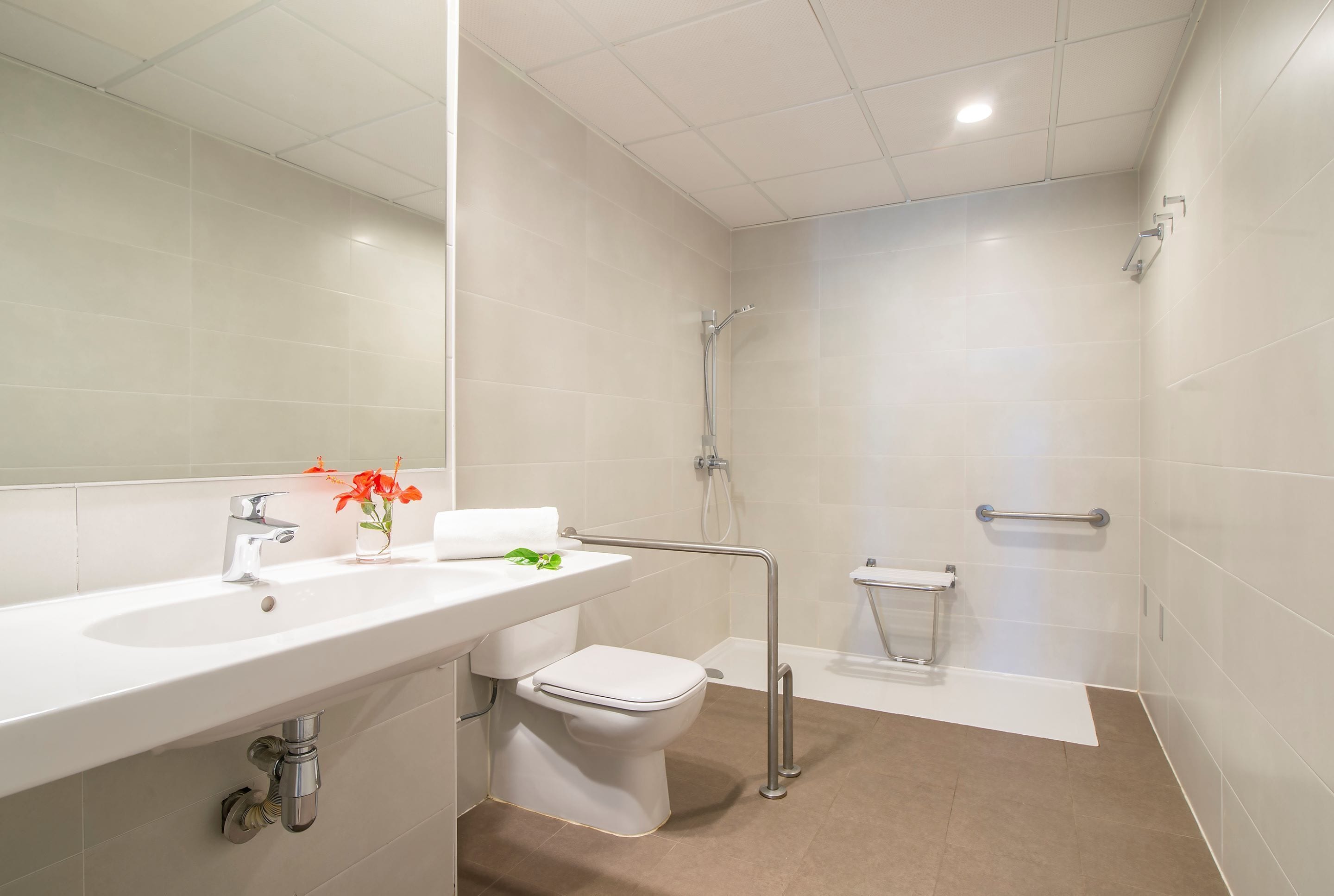 A modern bathroom with a white sink, toilet, and shower area.