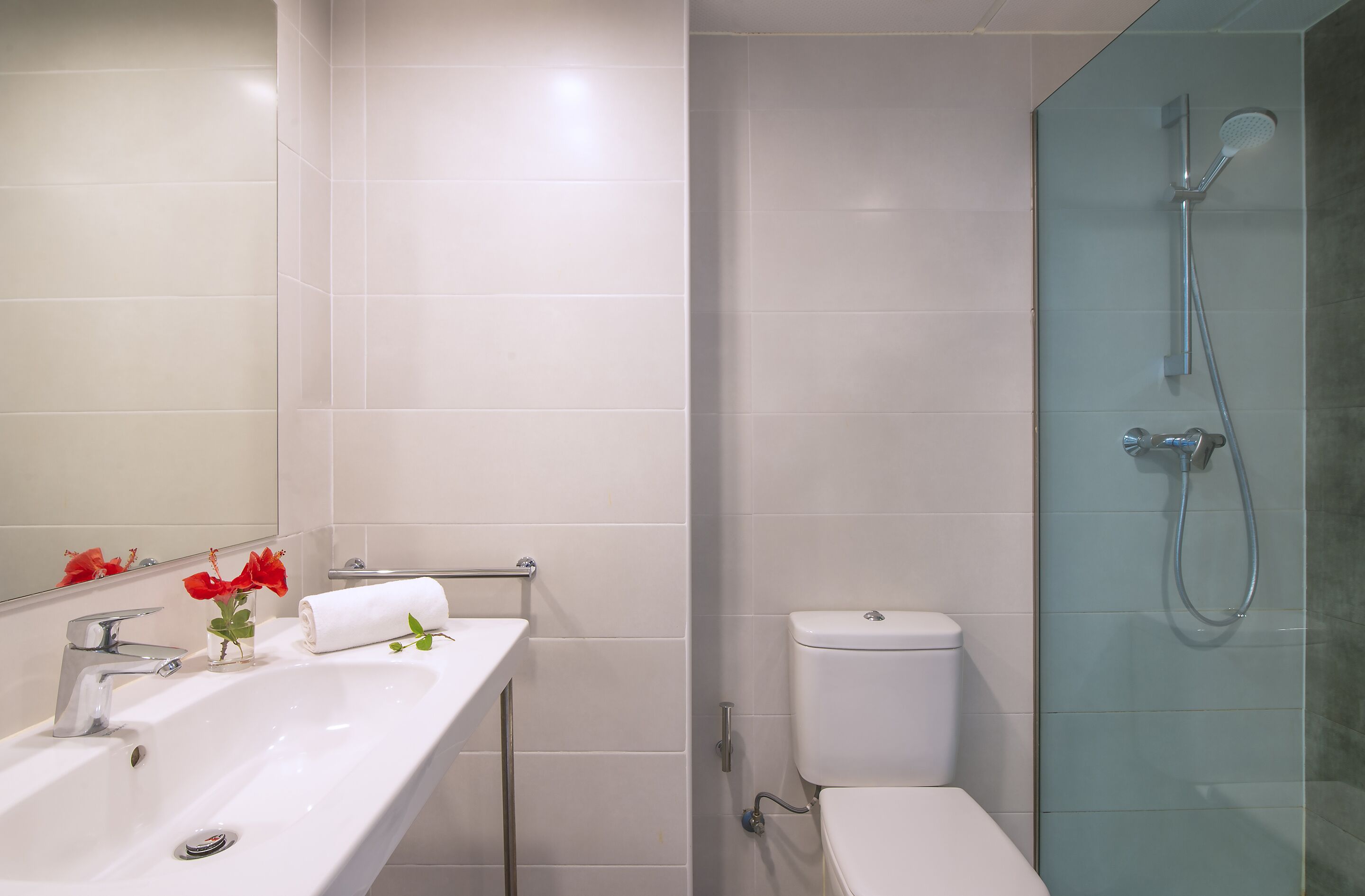 Un baño con lavamanos, espejo e inodoro blancos.