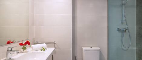Un baño con lavamanos, espejo e inodoro blancos.