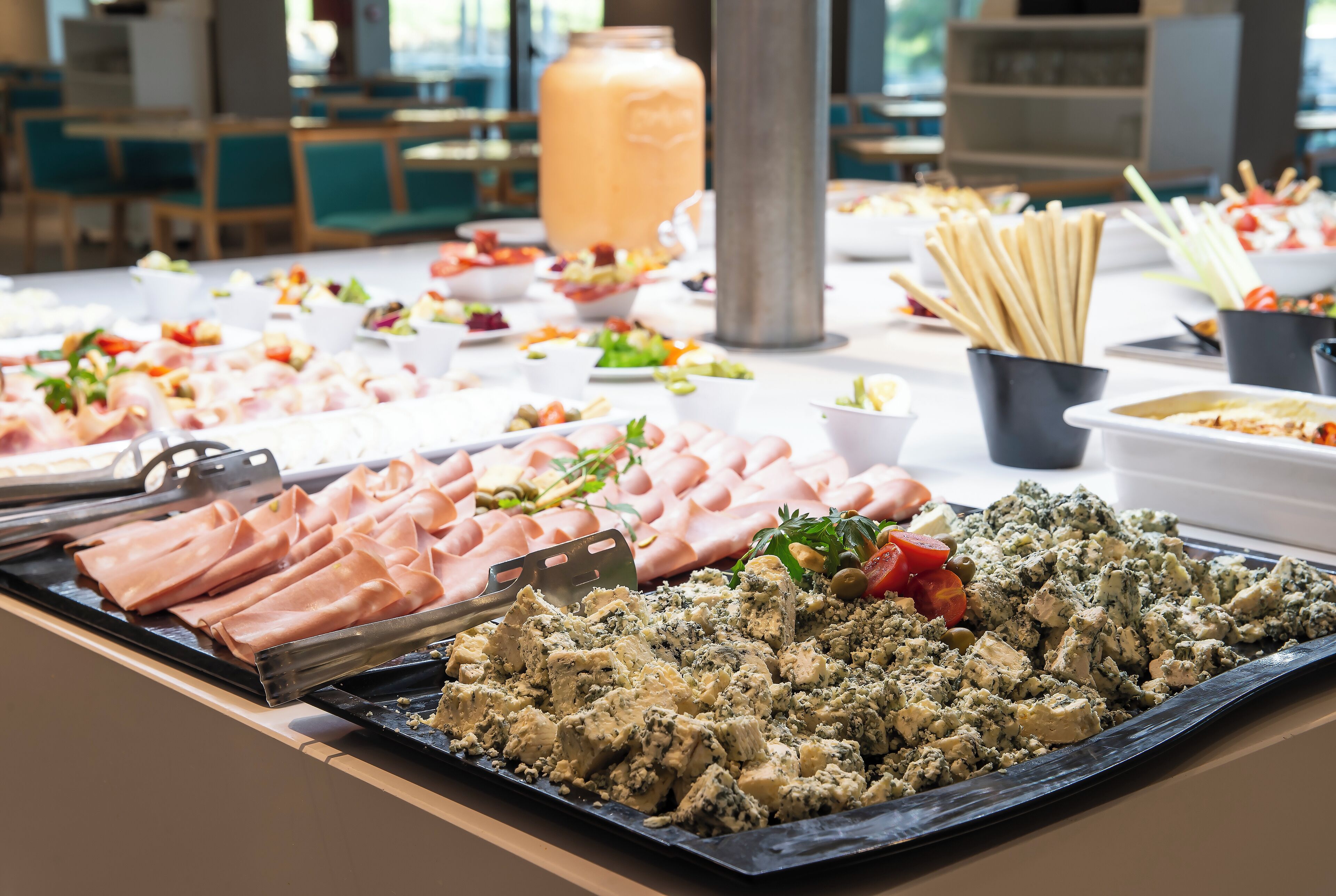 A buffet table with various food items including meats, cheeses, and salads.