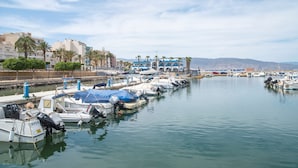 A marina with boats docked, a building with blue and white architecture, and palm trees along the waterfront. - Hotel Roquetas El Palmeral by Pierre & Vacances (Roquetas de Mar)