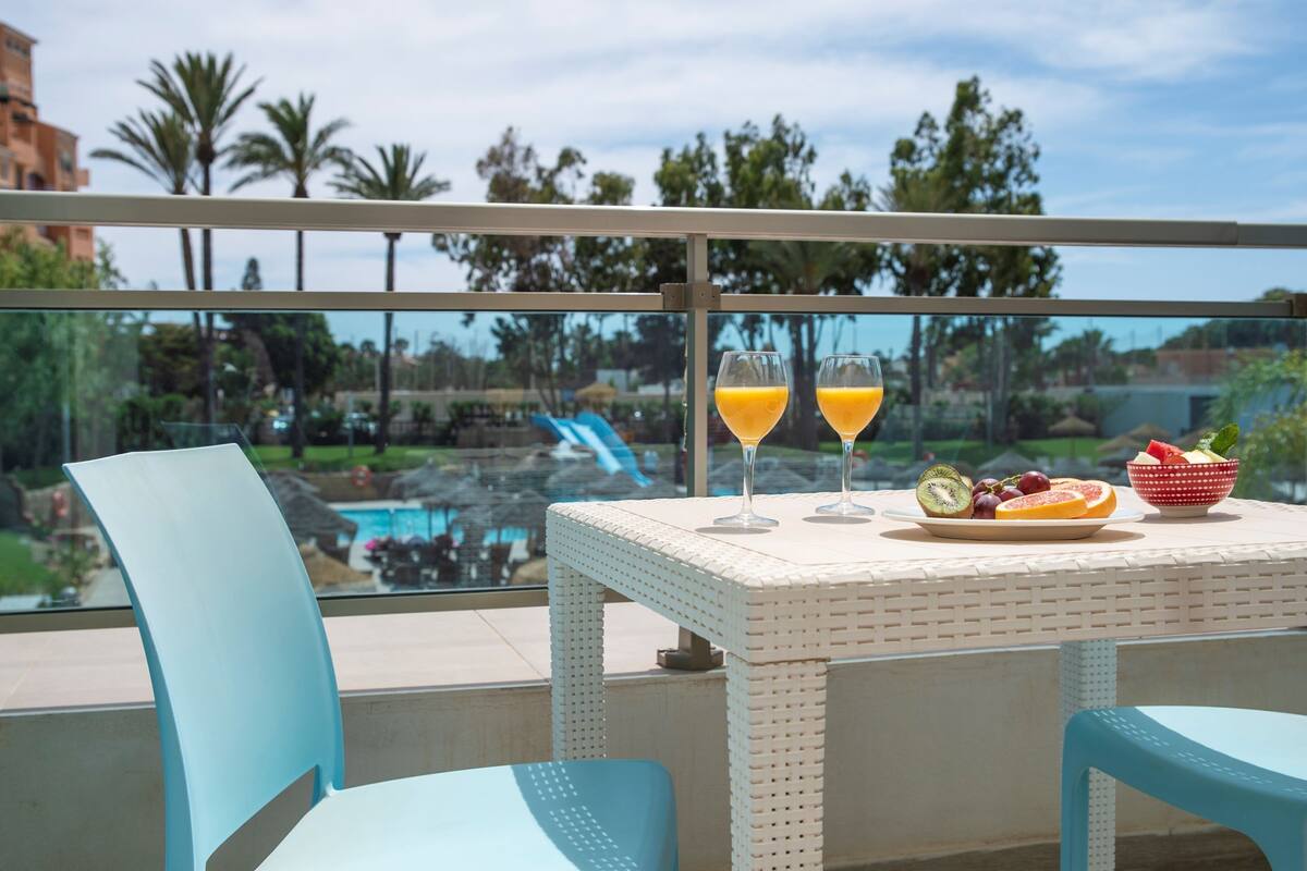 Ein Balkon mit Tisch für zwei Personen, ausgestattet mit einer Obstschale und zwei Gläsern Orangensaft.
