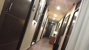 A hotel hallway with wooden flooring, dark doors, and recessed ceiling lighting. - Hostal Larios (Málaga)