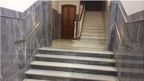 A marble staircase with handrails, leading to a wooden door at the top. - Hostal Larios (Málaga)