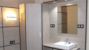A modern bathroom with a large mirror, a white sink, and a towel rack. - Hostal Larios (Málaga)