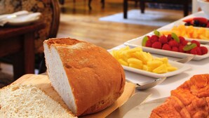 A dining table with bread, fruits, and a croissant. - Willance House Guest House (Richmond)