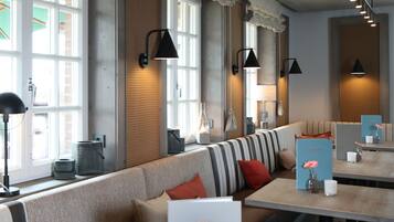 Ein modernes Interieur mit einem langen, gestreiften Sofa, einem Holztisch und schwarzen Wandleuchten.