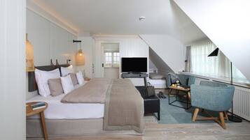 A modern hotel room with a large bed, a desk, a chair, and a TV.
