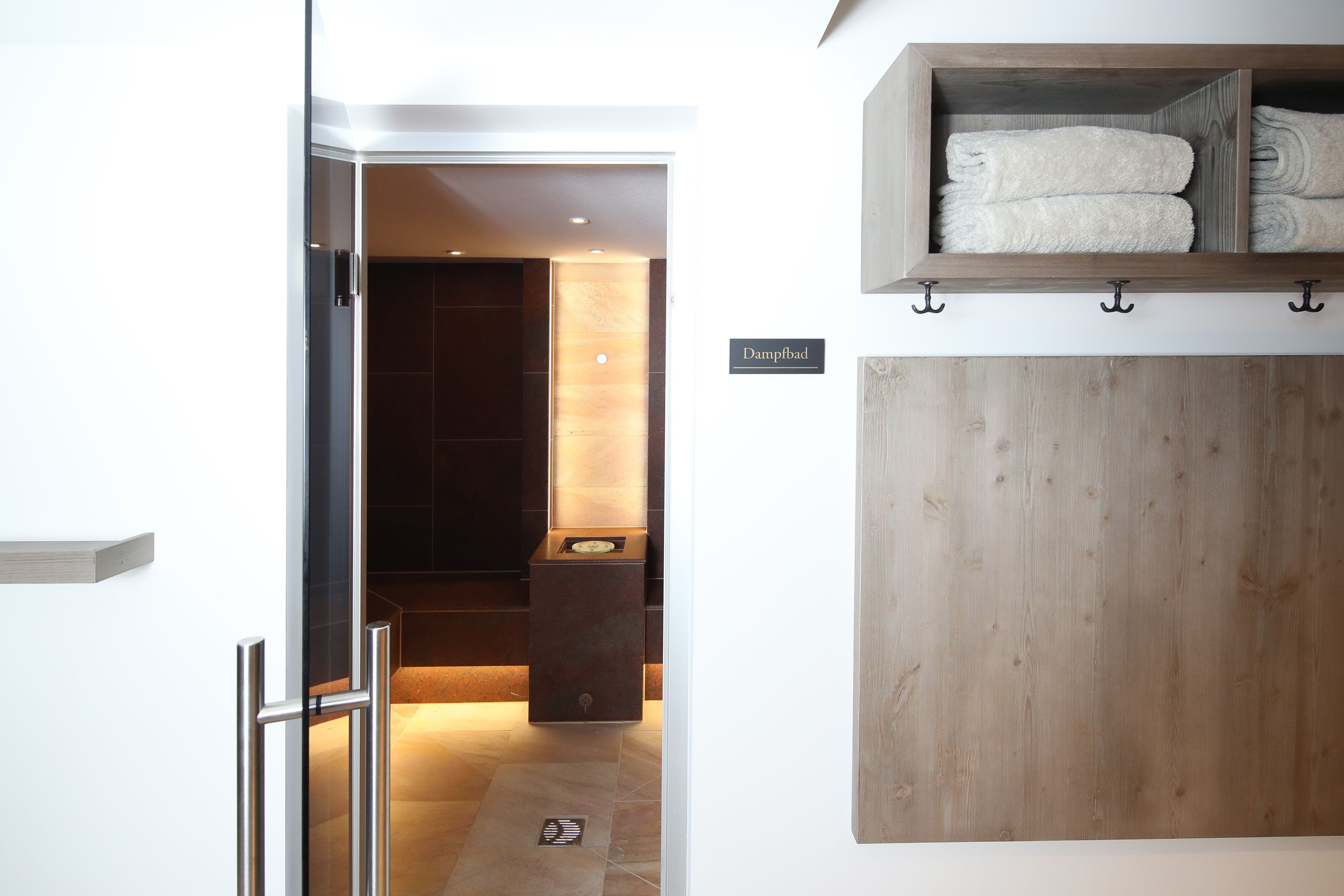 Un baño de hotel con tocador de madera, un perchero y un cartel que dice "Dampfbad".