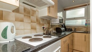 A kitchen with a stove, microwave, and kettle. - Lynton Apartments (Blackpool)