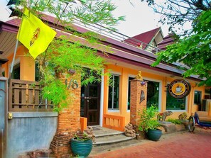 A building with a yellow flag, a brick facade, and a sign for a coffee shop. - Aiyara House (Ayutthaya)
