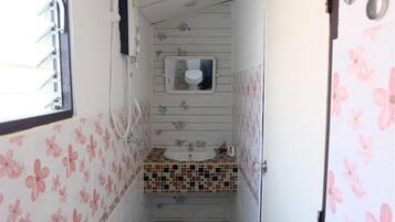 A narrow bathroom with a toilet, sink, and shower.