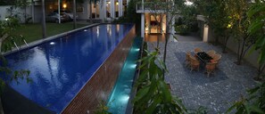 Une piscine avec une terrasse carrelée et un coin repas équipé de chaises en osier.
