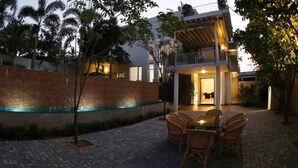 A modern house with a brick wall, a covered patio with wicker chairs, and a balcony. - Capital Villa (Battaramulla)