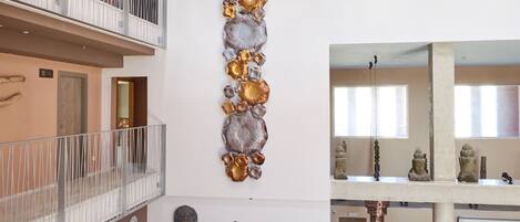 A multi-level interior with a balcony, a wall-mounted sculpture, and a series of statues.