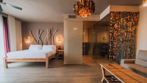 Una habitación de hotel moderna con una cama de madera, ducha de vidrio y una decoración de pared original.