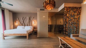 A modern hotel room with a wooden bed, a glass shower, and a unique wall decoration.