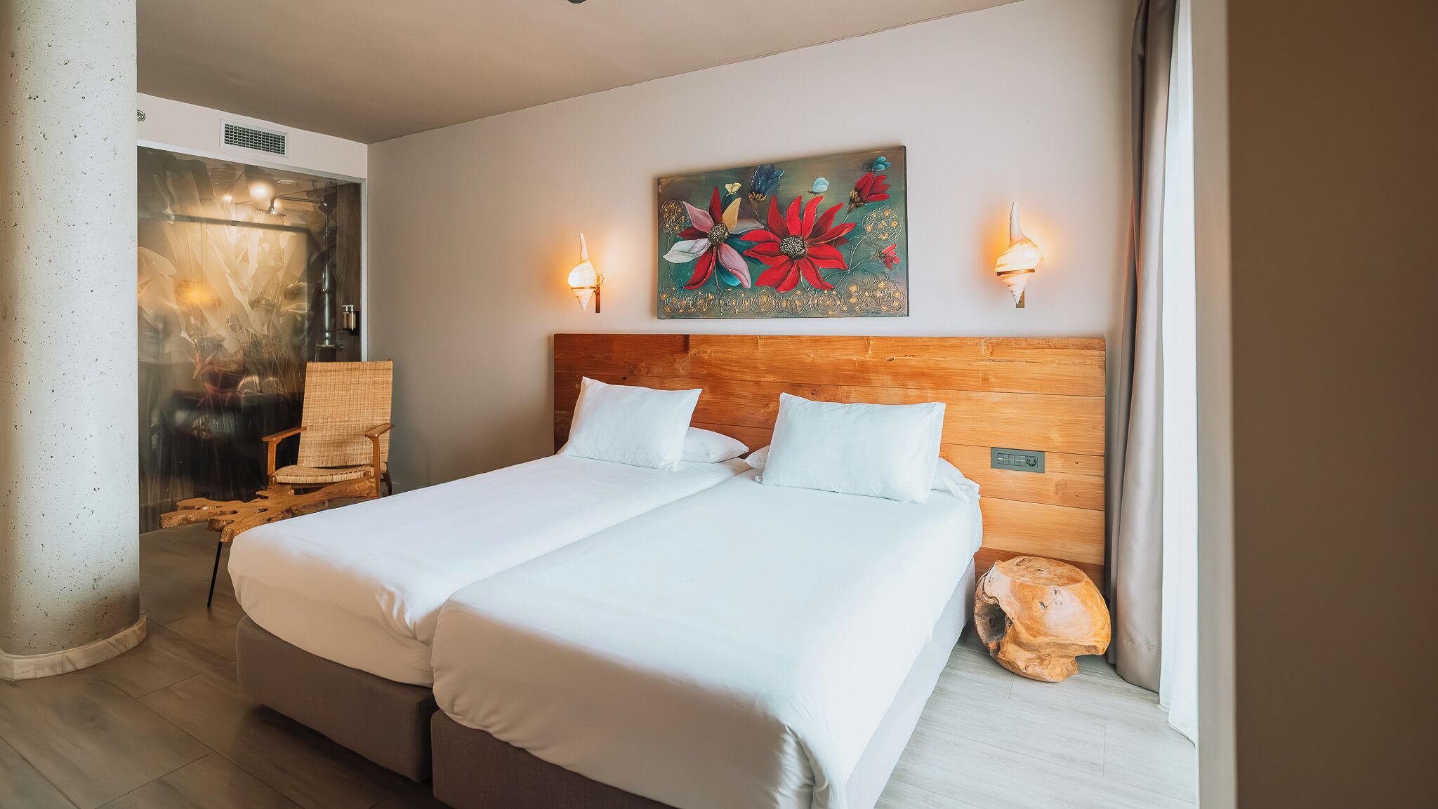 A hotel room with a double bed, a wooden headboard, two wall-mounted lights, and a painting above the bed.