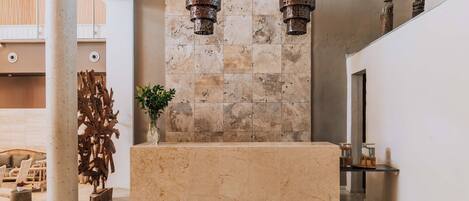 A reception area with a marble counter, a wooden sculpture, and hanging metal lanterns.