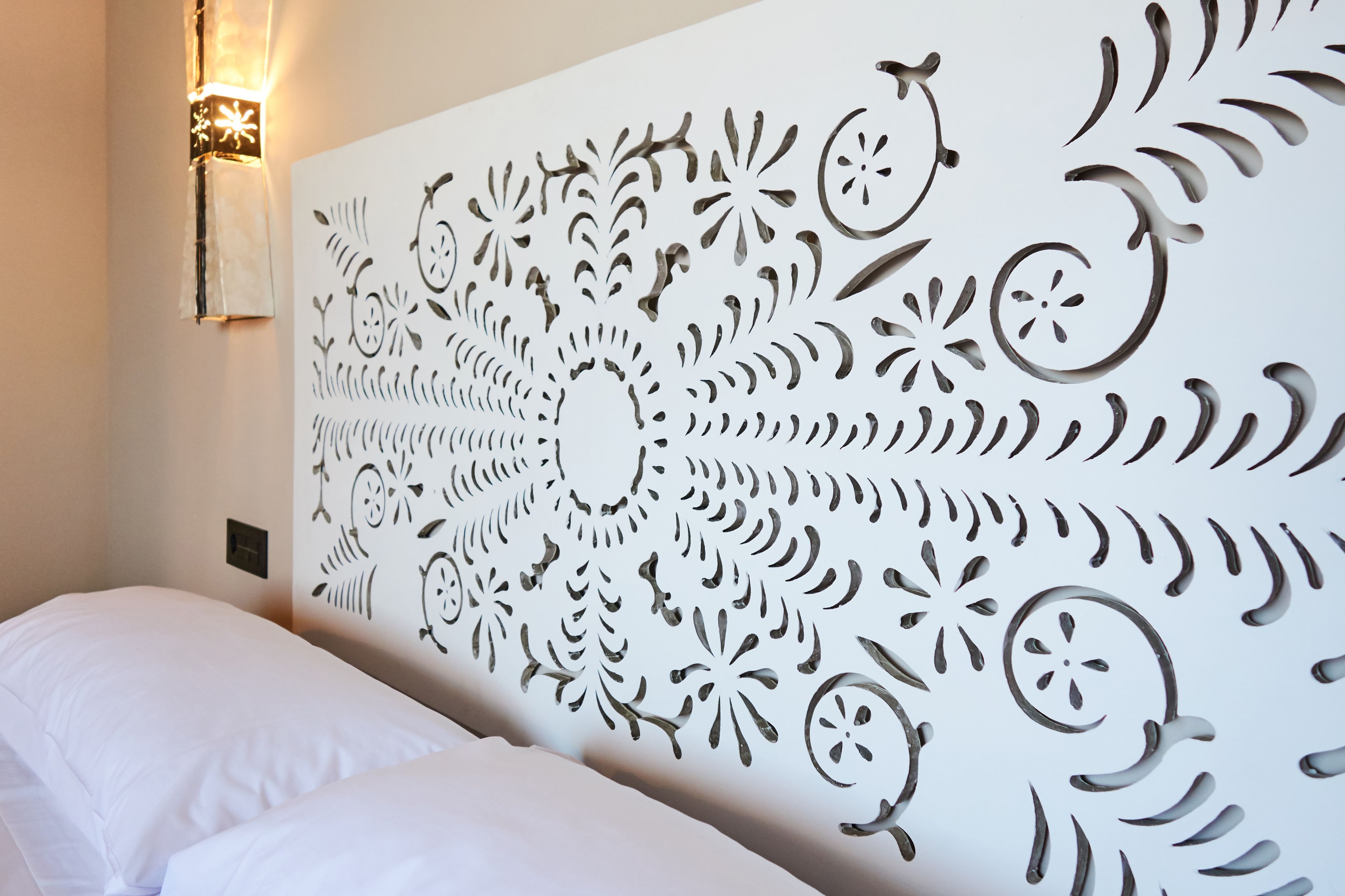 Una stanza con un letto bianco e un pannello decorativo a parete con elaborati intagli.