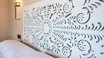 Una stanza con un letto bianco e un pannello decorativo a parete con elaborati intagli.