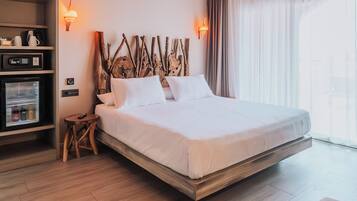 Una camera d'albergo con un letto, un minibar, un tavolino e una lampada fissata alla parete.