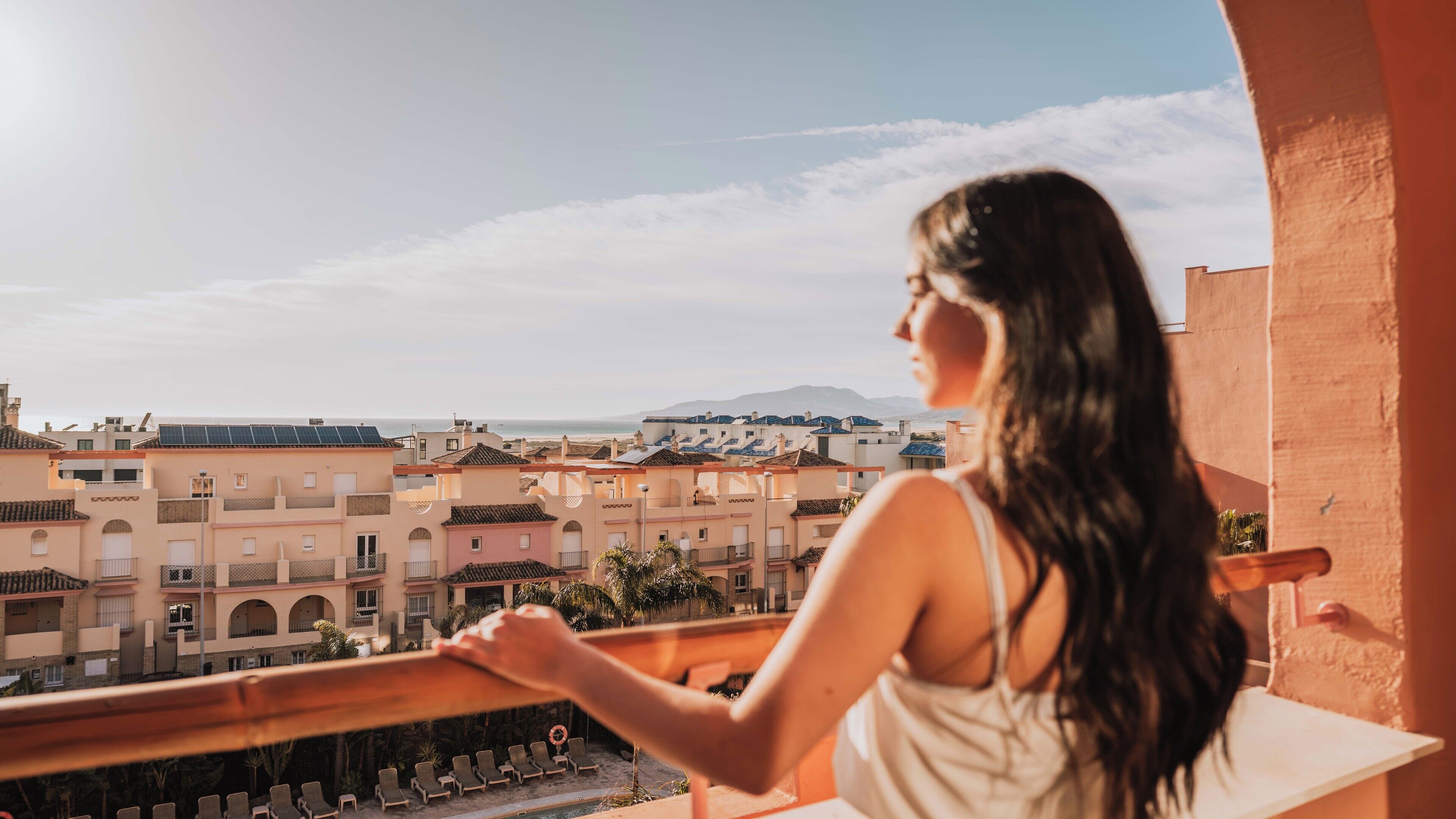 A balcony with a view of a coastal town, including buildings and a beach.