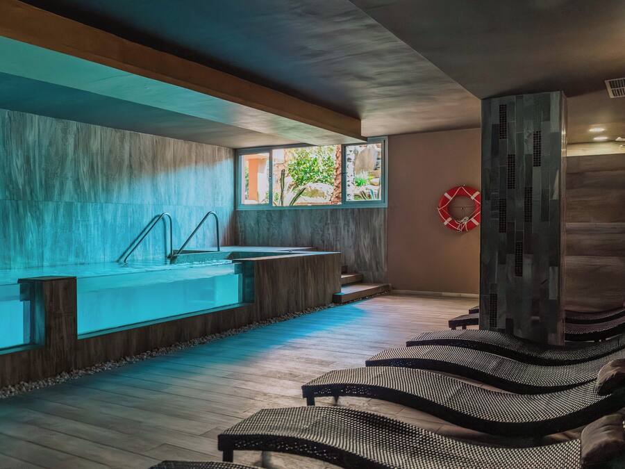 A spa area with a large bathtub, wooden flooring, and lounge chairs.